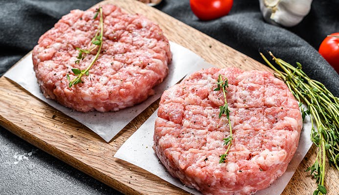 Raw chicken patty, ground meat cutlets on a chopping Board. Organic mince. Black background. Top view