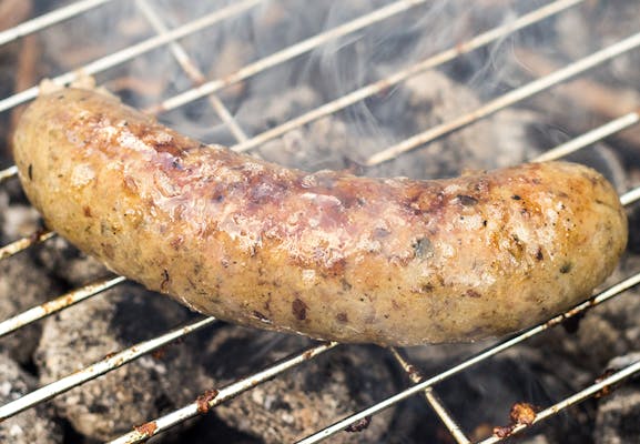 Grilling white sausages with herbs on a barbecue