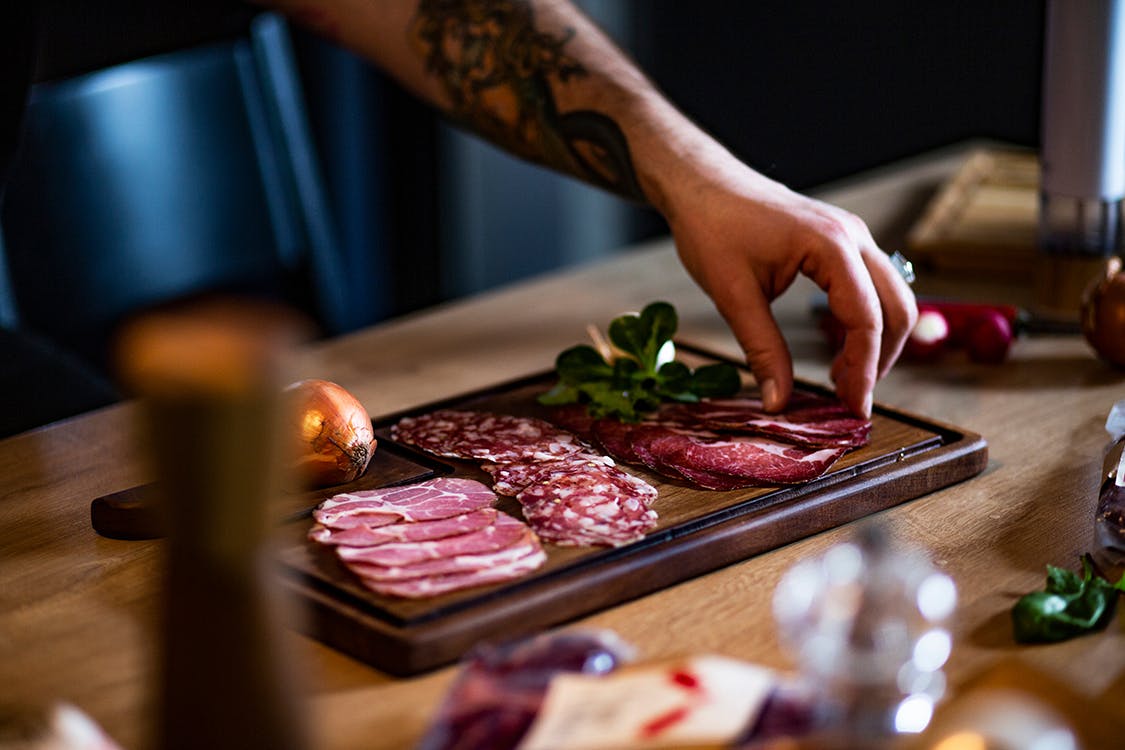 hand taking meat from charcuterie board