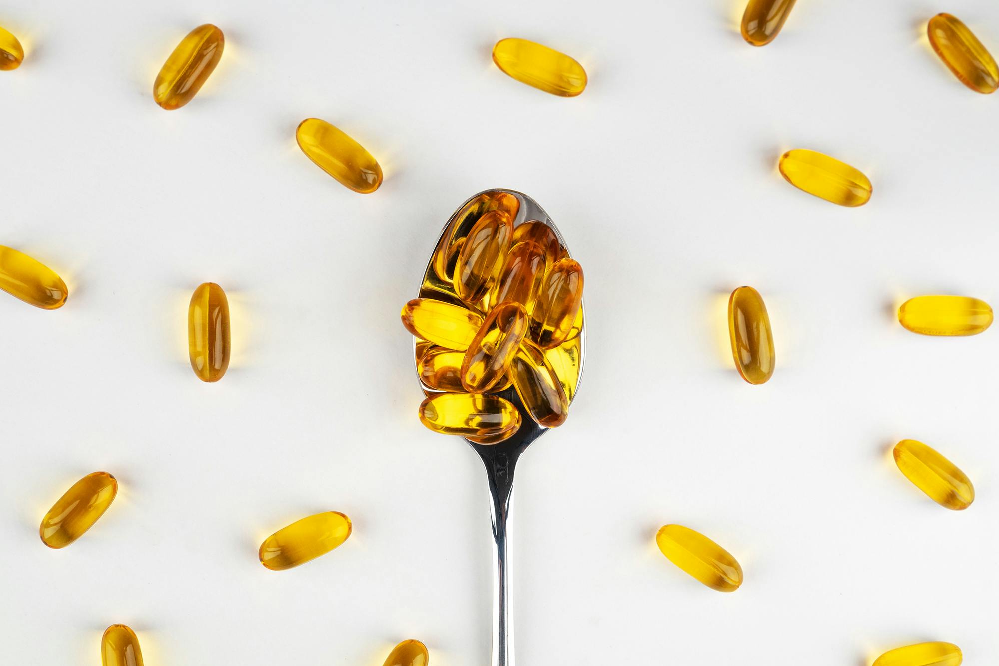 Omega 3 fish oil capsules on a spoon on a light background