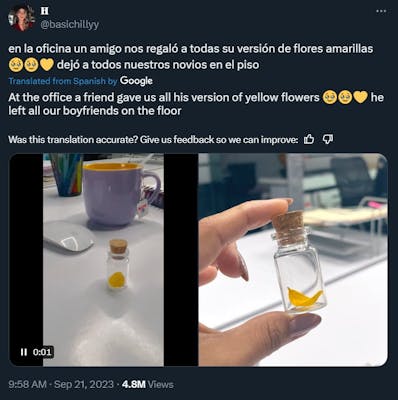 Man leaves a small vial with a yellow flower pedal to female coworkers