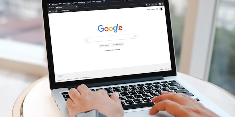 A man is typing on Google search engine from a laptop