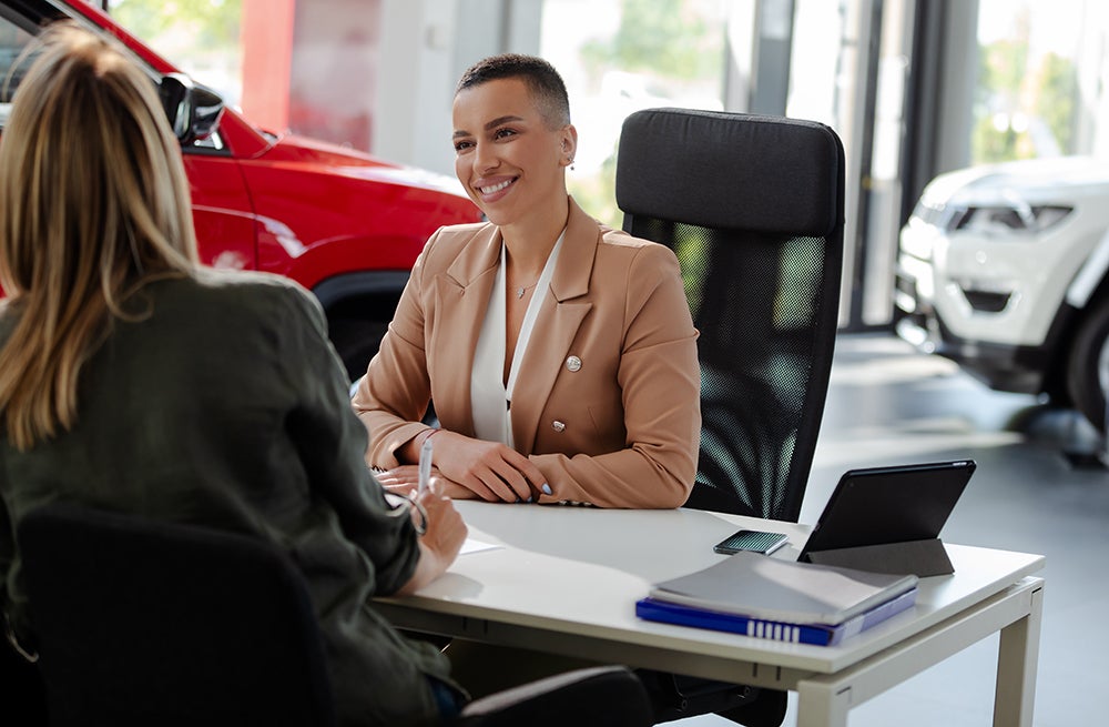 Smiling car rental assistant giving information to customer.