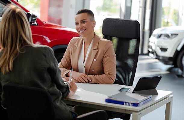 Smiling car rental assistant giving information to customer.