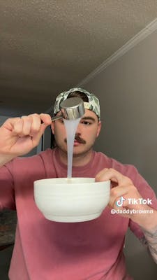 man pouring substance into bowl from measuring cup