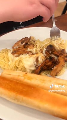 fork in pasta with chicken and a breadstick
