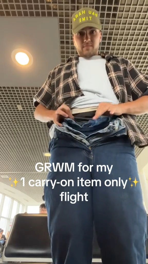young man wearing multiple pairs of pants with caption 'GRWM for my 1 carry-on item only flight'