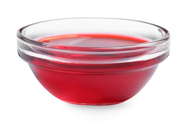 Glass bowl with red food coloring isolated on white