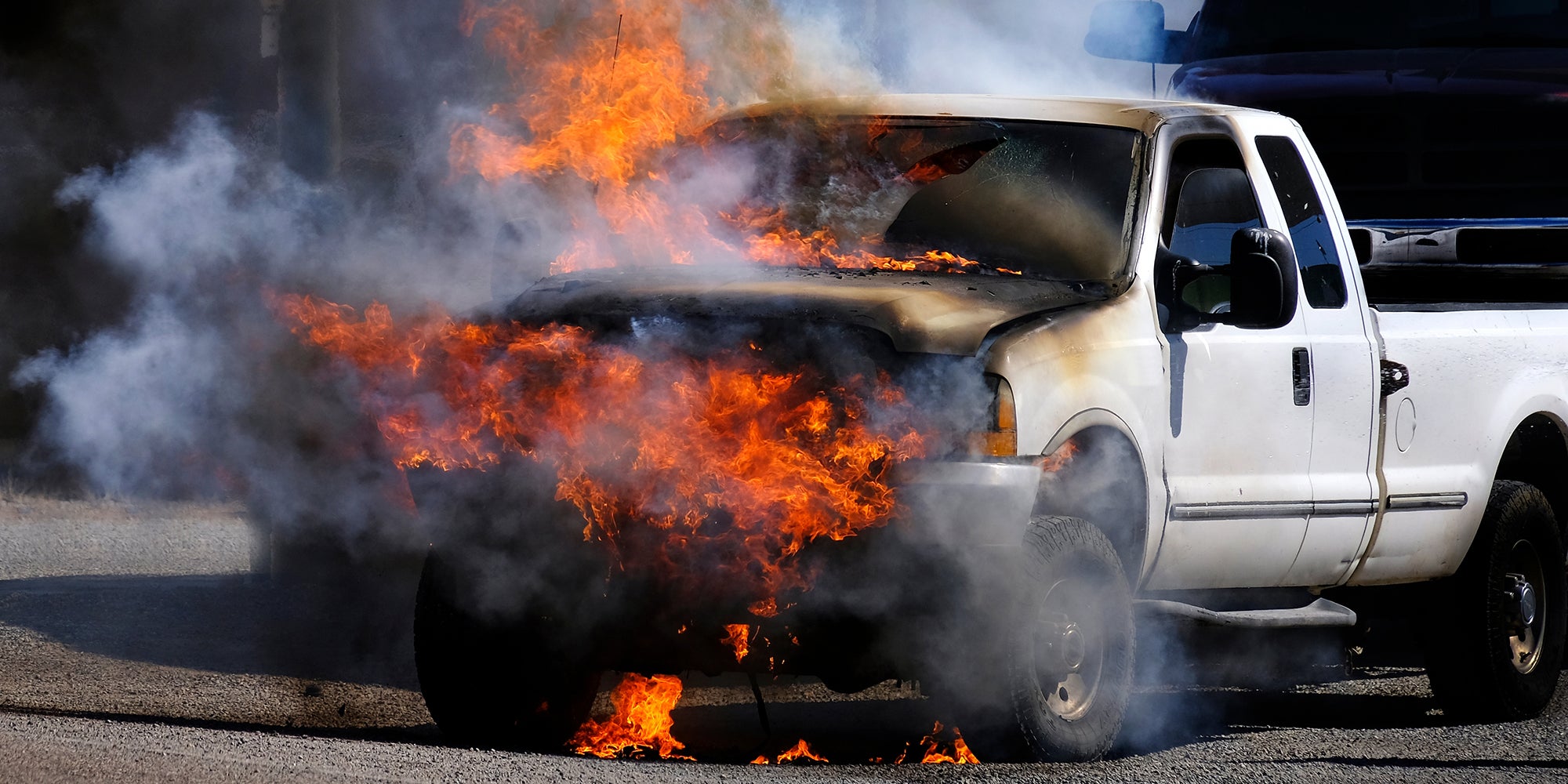 Truck vehicle on fire burning in flames billowing smoke destroyed on roadway