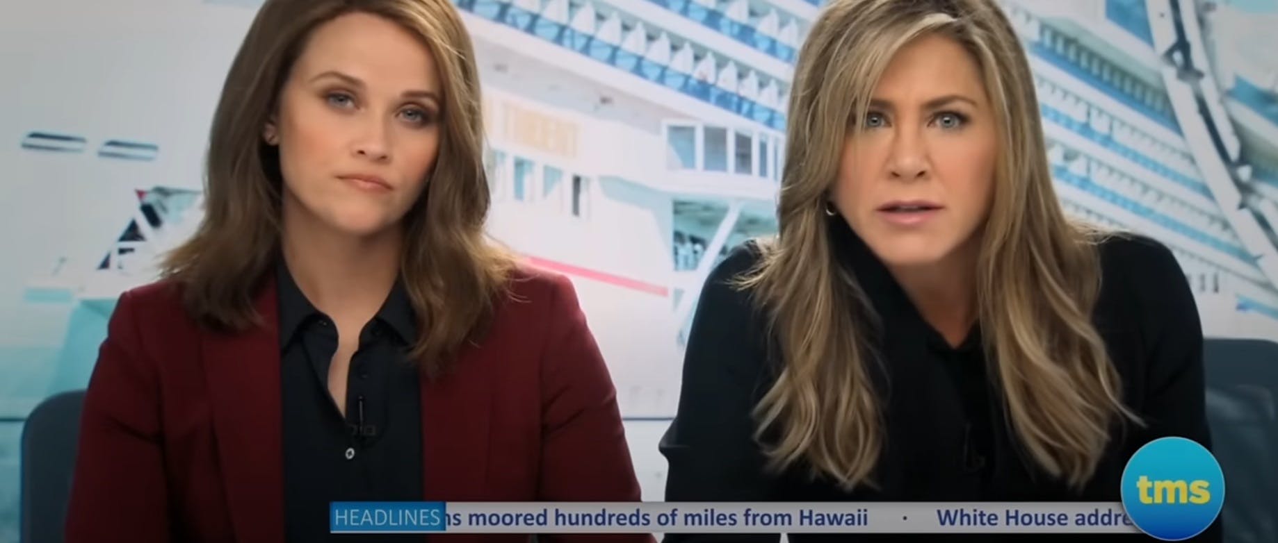 Reese Witherspoon and Jennifer Aniston sitting at a news desk together in a scene from 'The Morning Show'