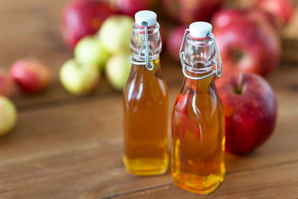 glass bottles of vinegar on table with apples