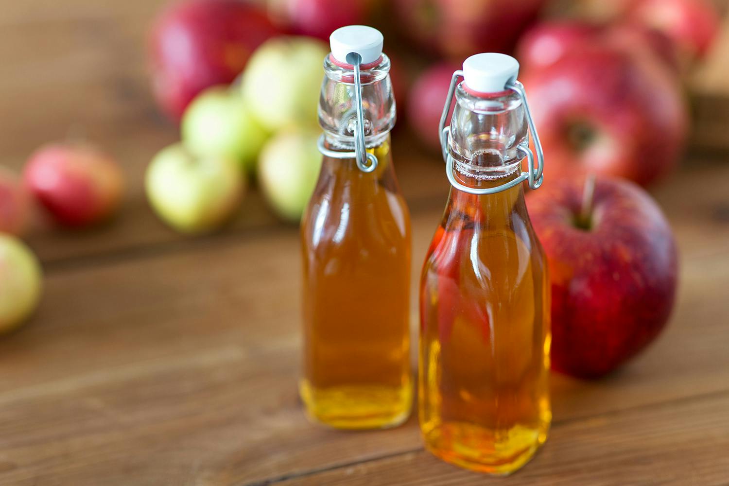 glass bottles of vinegar on table with apples