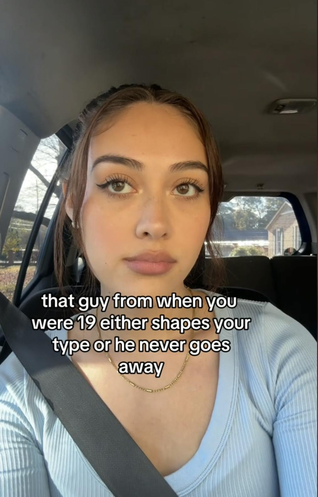 A woman sitting in her car staring off into the distance. Text overlay reads, 'that guy from when you were 19 either shapes your type or he never goes away'
