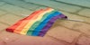 discarded mini gay rainbow flag on ground after a protest march, made with generative ai