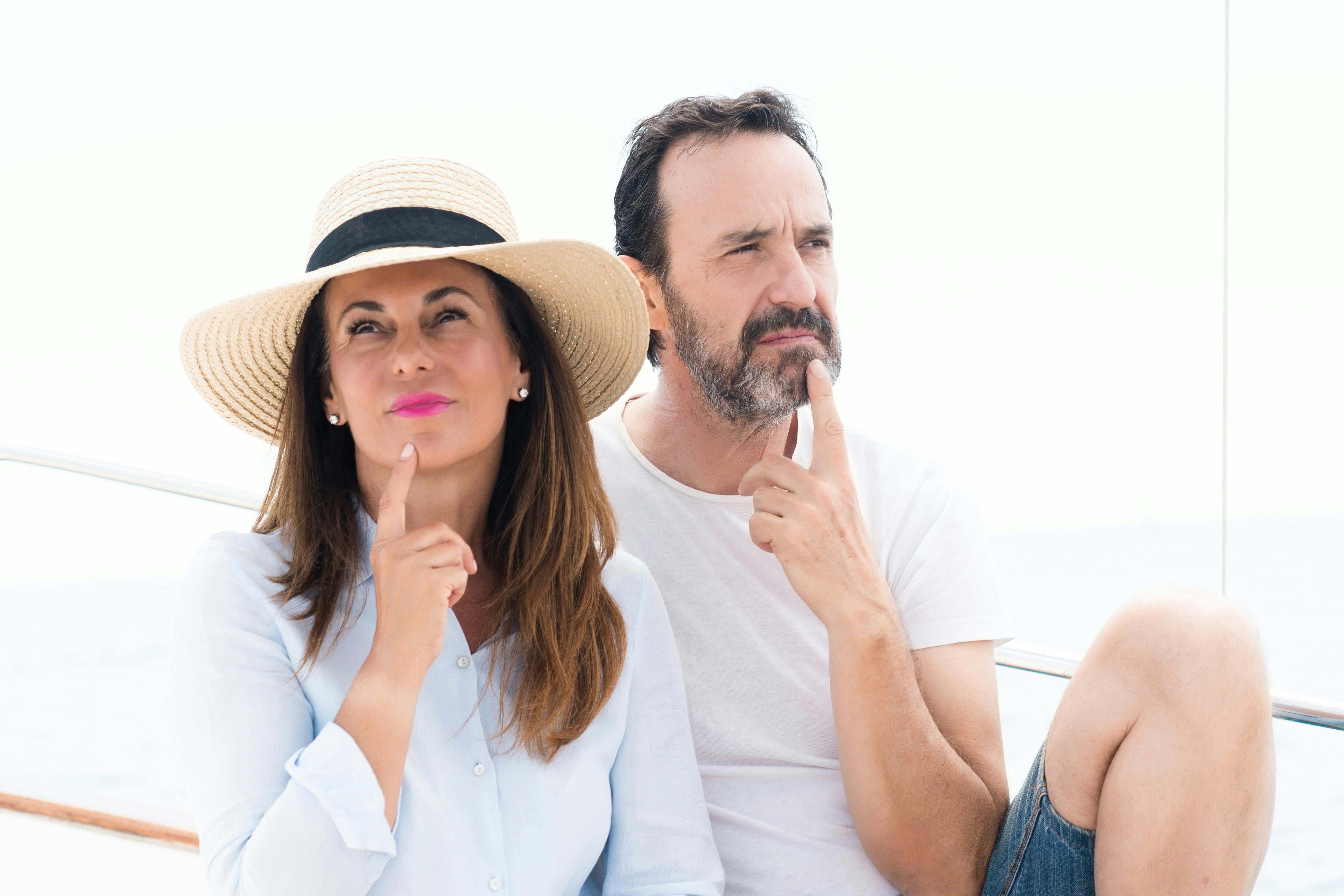 Middle age couple traveling on sailboat serious face thinking about question, very confused idea