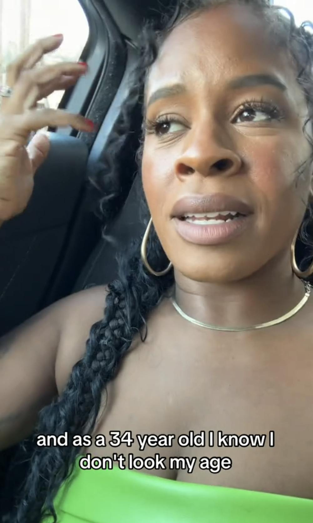 A Black woman in her club outfit in the back of a taxi looking exasperatedly off-camera. Text overlay reads, 'and as a 34 year old I know I don't look my age'