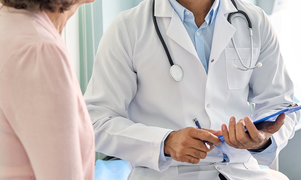 medical worker therapist in white doctor's robe having appointment consulting older female patient in modern clinic hospital. Medical healthcare concept.