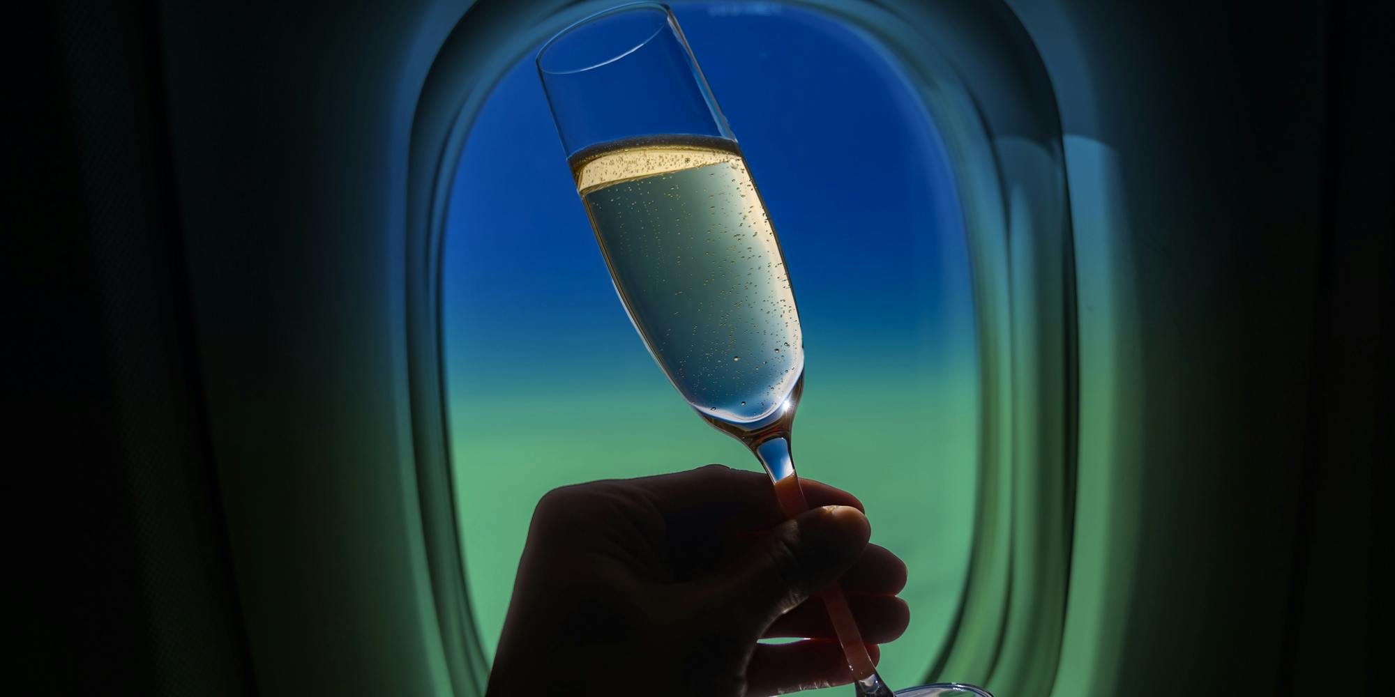 Hand holding champagne on plane