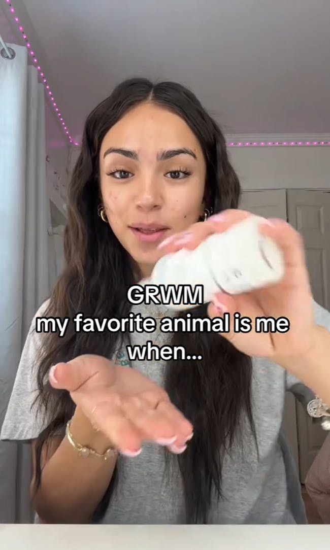 A brown haired woman about to put moisturizer on her face. Text reads, 'GRWM my favorite animal is me when...'