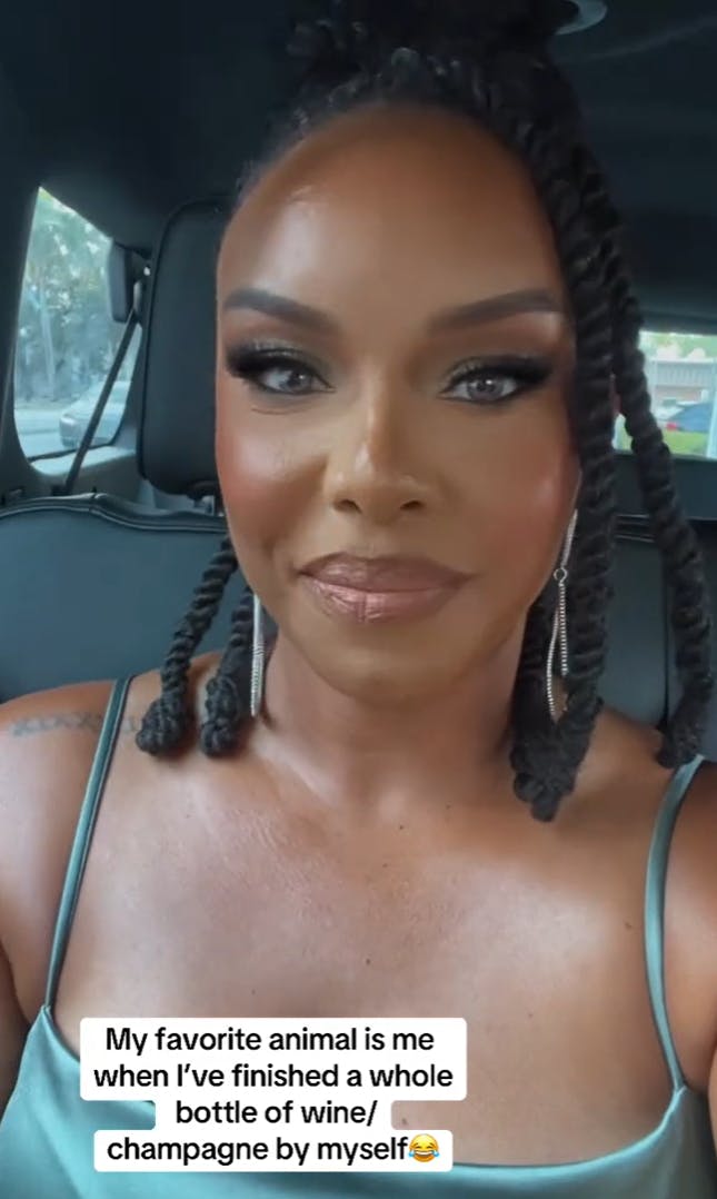 A Black woman with perfect makeup sitting in the car looking at the camera. Text overlay reads, 'My favorite animal is me when I've finished a whole bottle of wine/champagne by myself.'