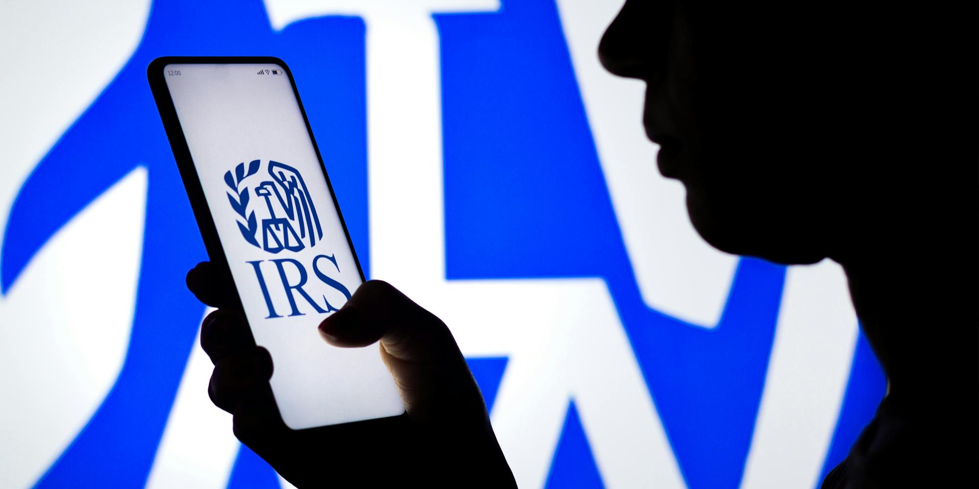 Silhouette of person holding phone with Irs logo on it