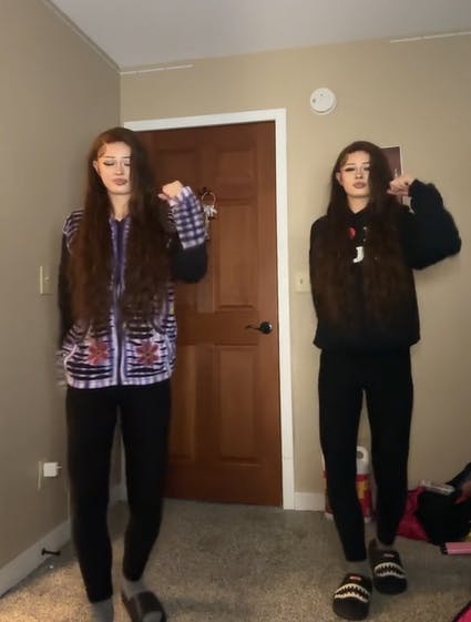 Screenshot of twins dancing in a corner of a room.