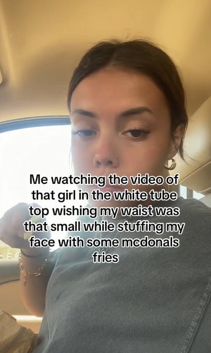 Screenshot of a woman eating french fries in a car. Text overlay reads, 'Me watching the video of that girl in the white tube top wishing my waist was that small while stuffing my face with some mcdonals fries.'