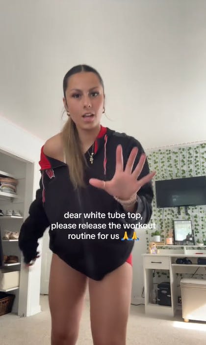 Screenshot of a woman dancing with text overlay that reads, 'dear white tube top, please release the workout routine for us.'