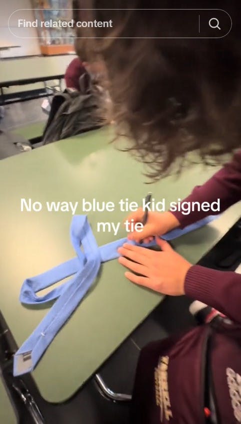 blue tie kid signing a blue tie