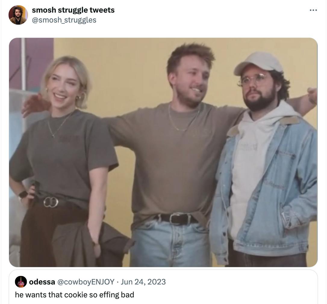 Trio of people from Smosh standing on a stage, the man in the center looking to the side at one of the others, similar to the 'he wants that cookie so bad' meme.