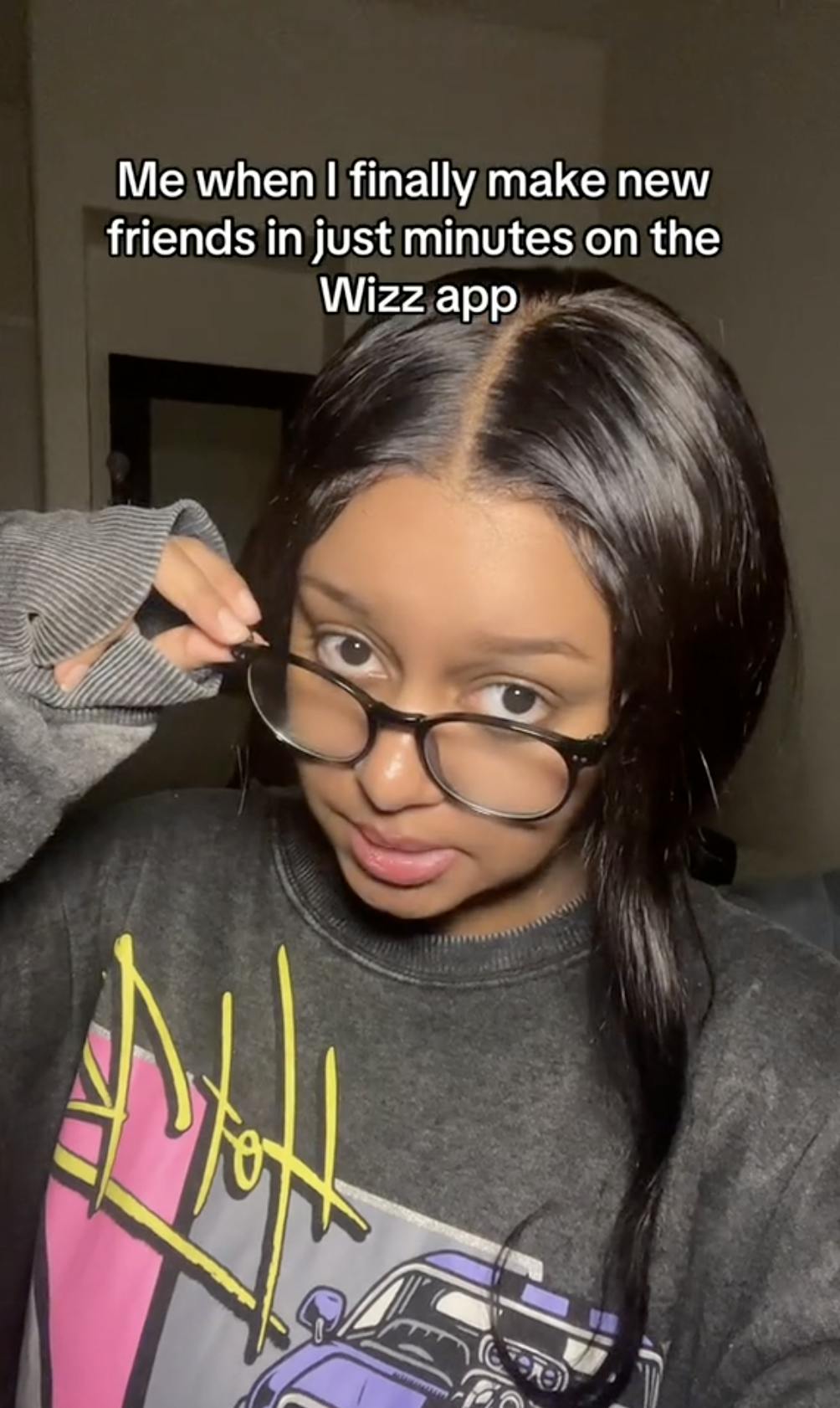 A young woman tilting down her glasses and staring over them at the camera. Text overlay reads, 'Me when I finally make new friends in just minutes on the Wizz app.'