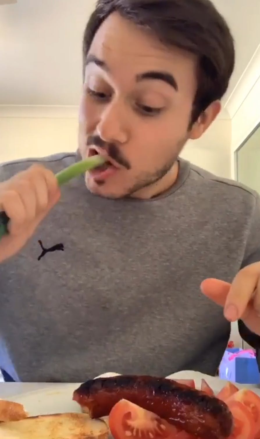 A man eating a Balkan Breakfast biting into a raw spring onion.