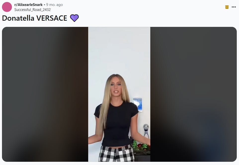 Donatella Versace purple heart meme with a screenshot of a woman in a black t-shirt.