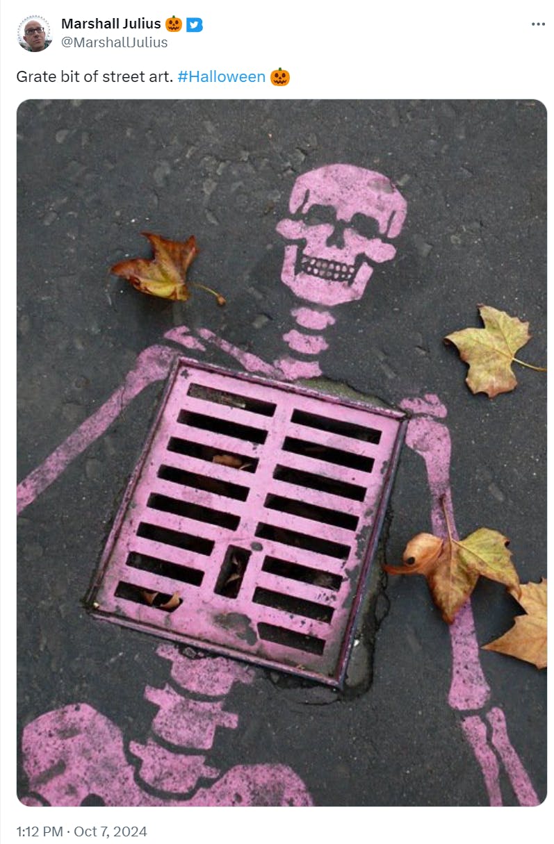 Photo of a spray painted pink skeleton over a grate on the road. Text reads, 'Grate bit of street art.'