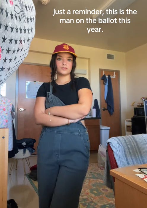 Women in overalls frowning into the camera with her arms crossed.