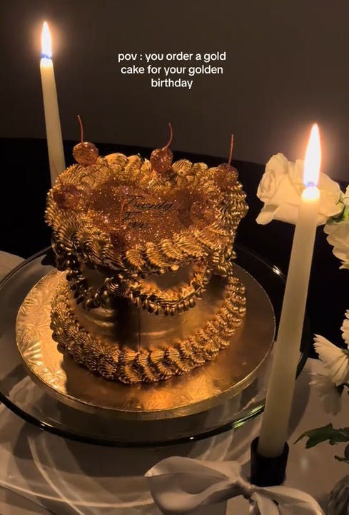 TikTok video showing a heart-shaped cake with gold frosting.