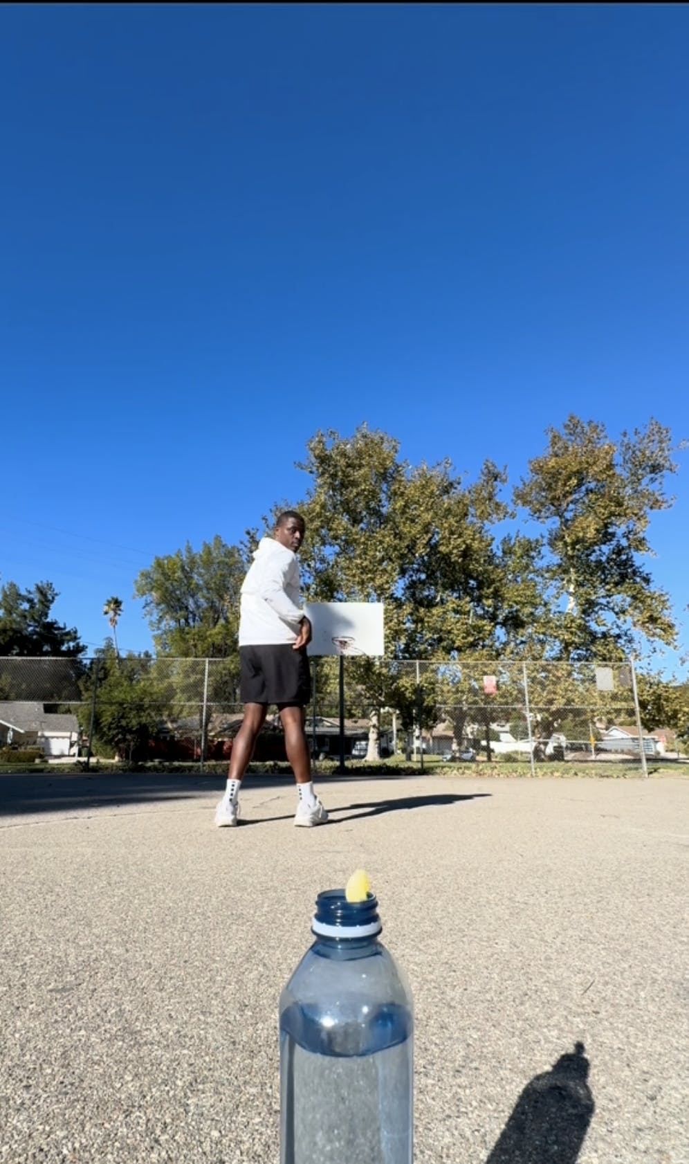 Lethal Shooter tossing a gummy bear into a water bottle with his back turned.