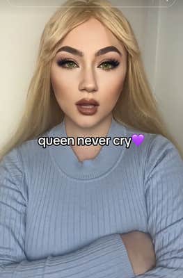 Video of a woman in a blue sweater and full makeup crossing her arms and speaking to the camera.