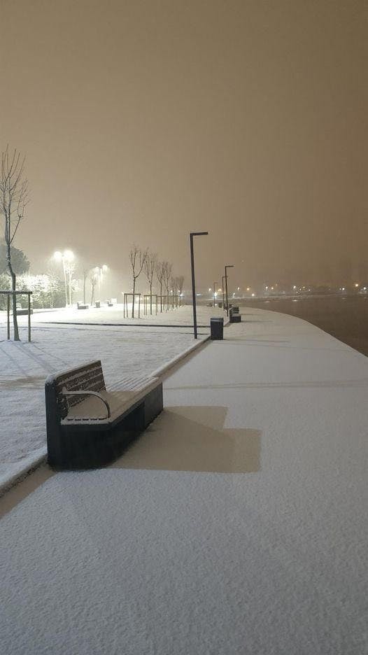 A photo of a snowy city embankment at night.