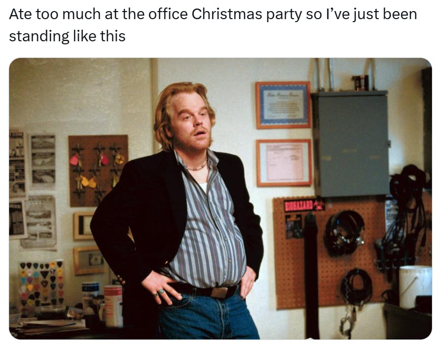 Christmas meme that reads, 'Ate too much at the office Christmas party so I’ve just been standing like this' with a photo of a man with a beer belly, his hands on his hips looking very tired.