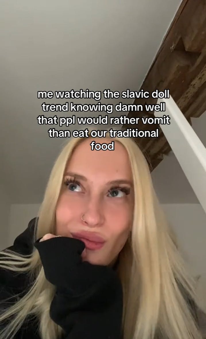 Blonde woman looking off to one side. Text overlay reads, 'me watching the slavic doll trend knowing damn well that ppl would rather vomit than eat our traditional food.'