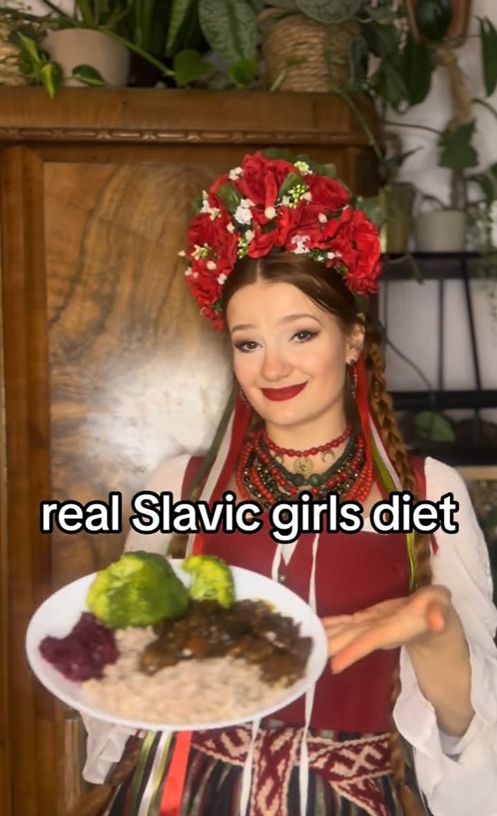 A woman in traditional clothing and head dress holding out a plate of food for the camera. Text overlay reads, 'real Slavic girls diet.'