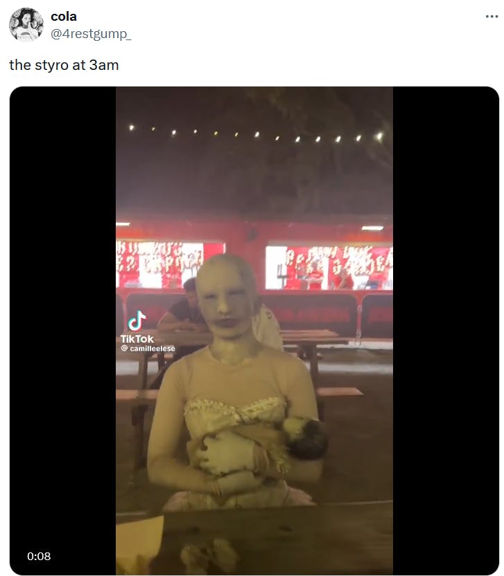 Tweet with a TikTok video of someone in a costume resembling a neglected doll holding a baby.