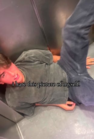 TikTok photo of a college guy drunk on the floor of an elevator. Text overlay reads, 'I hate this picture of myself.'