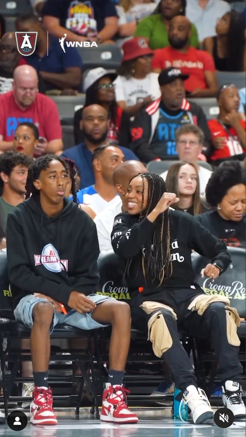 renee montgomery and her cousin dancing in their seats courtside at an atlanda dream game wnba