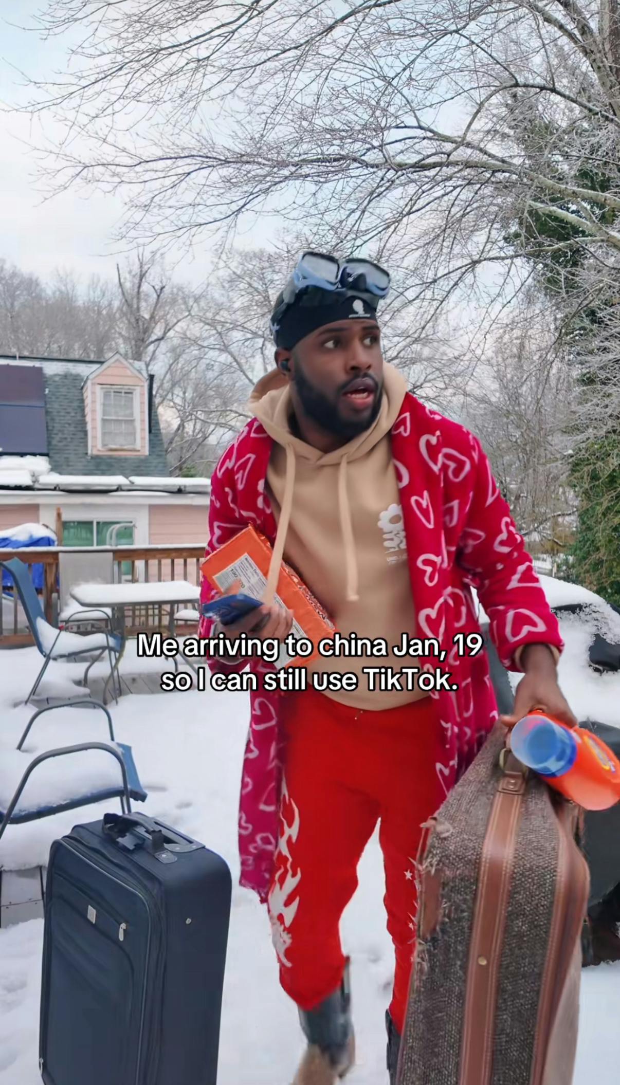 TikTok screenshot of a man in pyjamas rushing with suitcases in the snow. Text overlay reads, 'Me arriving to china Jan, 19 so I can still use TikTok.'