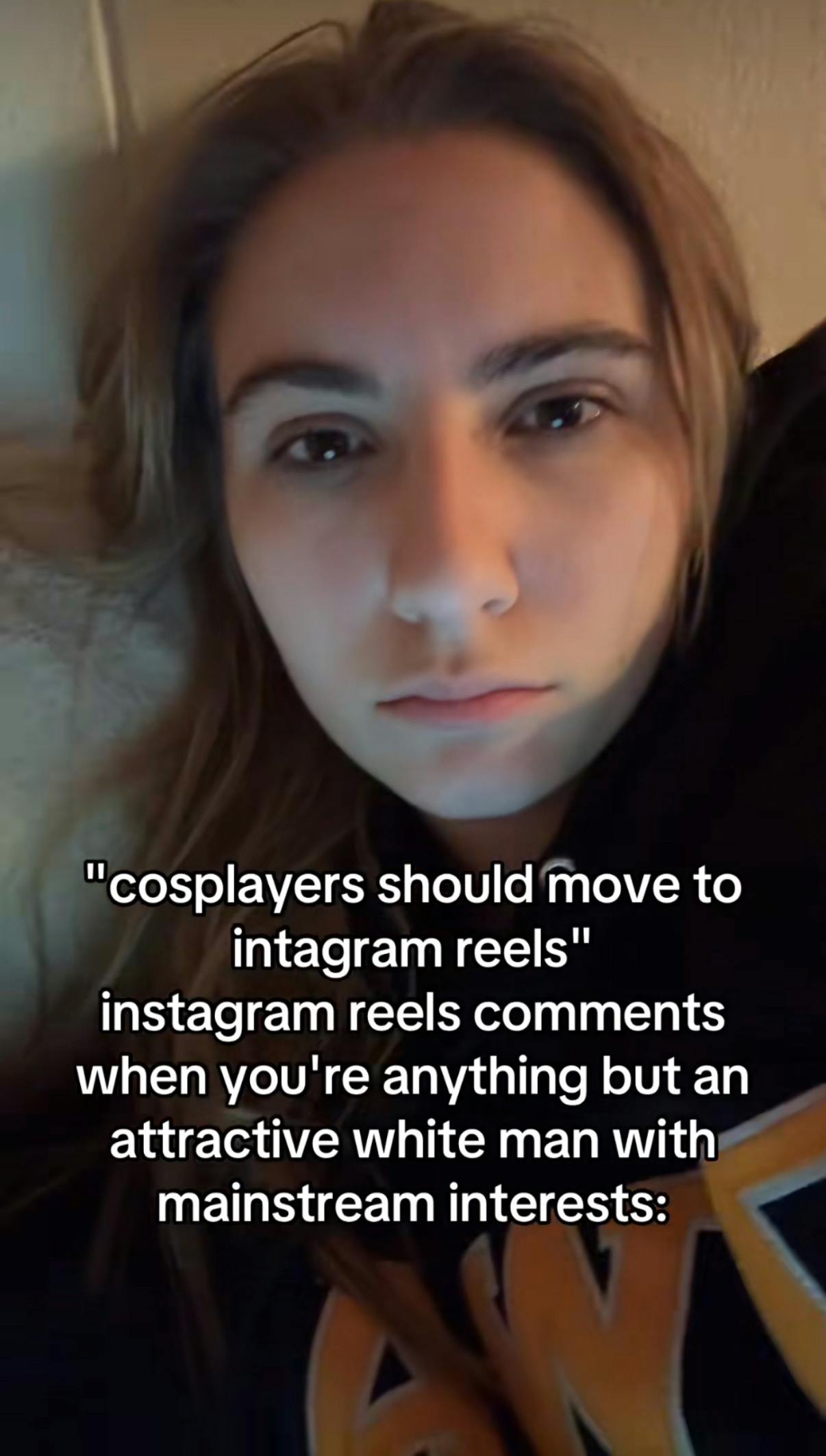 TikTok screenshot of a woman lying down, staring at the camera. Text overlay reads, ''cosplayers should move to instagram reels' instagram reels comments when you're anything but an attractive white man with mainstream interests:' as audio plays saying, 'Women are stupid and I don’t respect them.'