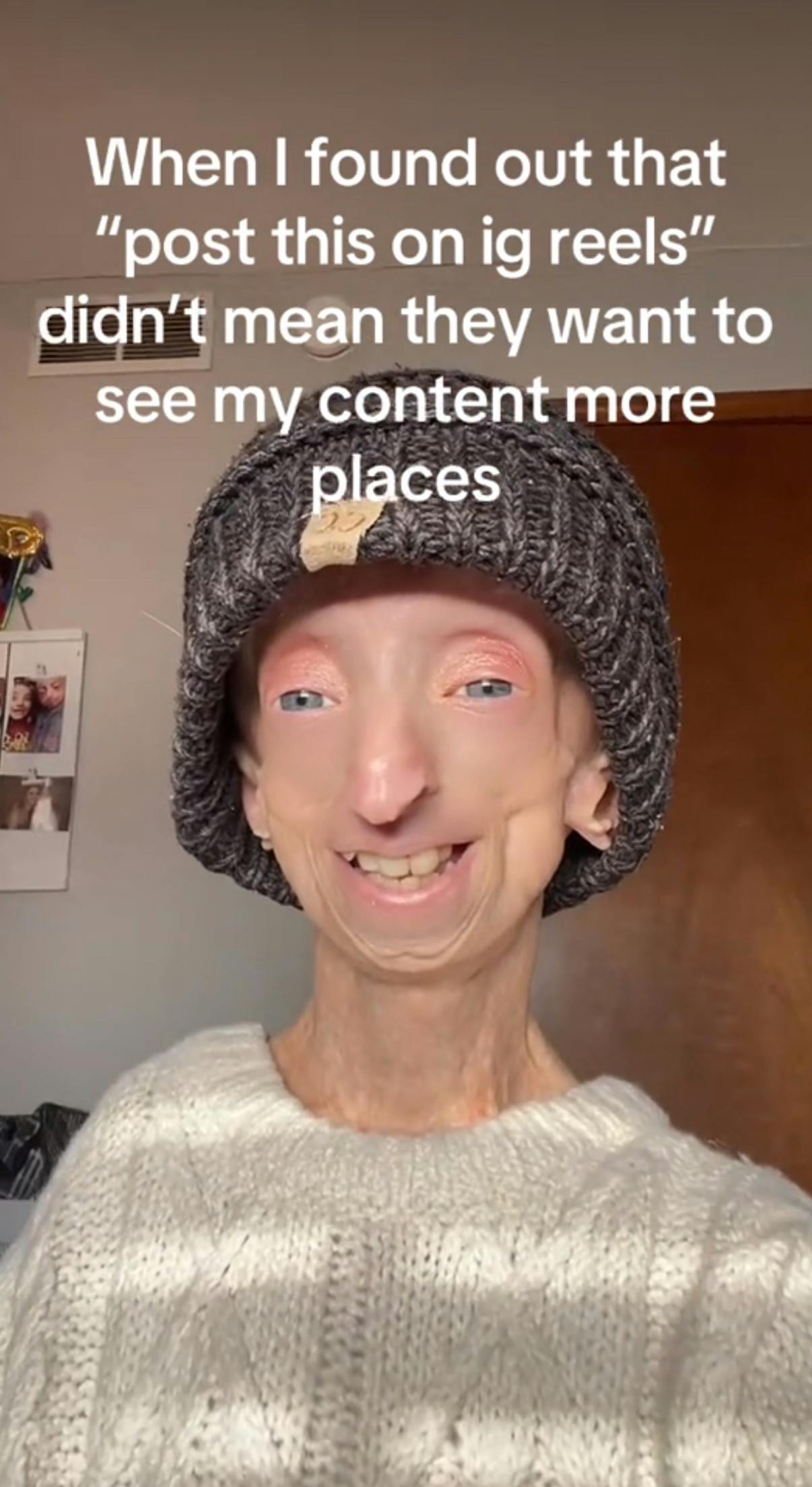 TikTok screenshot of a woman wearing a grey beanie smiling at the camera. Text overlay reads, 'When I found out that 'post this on ig reels' didn't mean they want to see my content more places.'