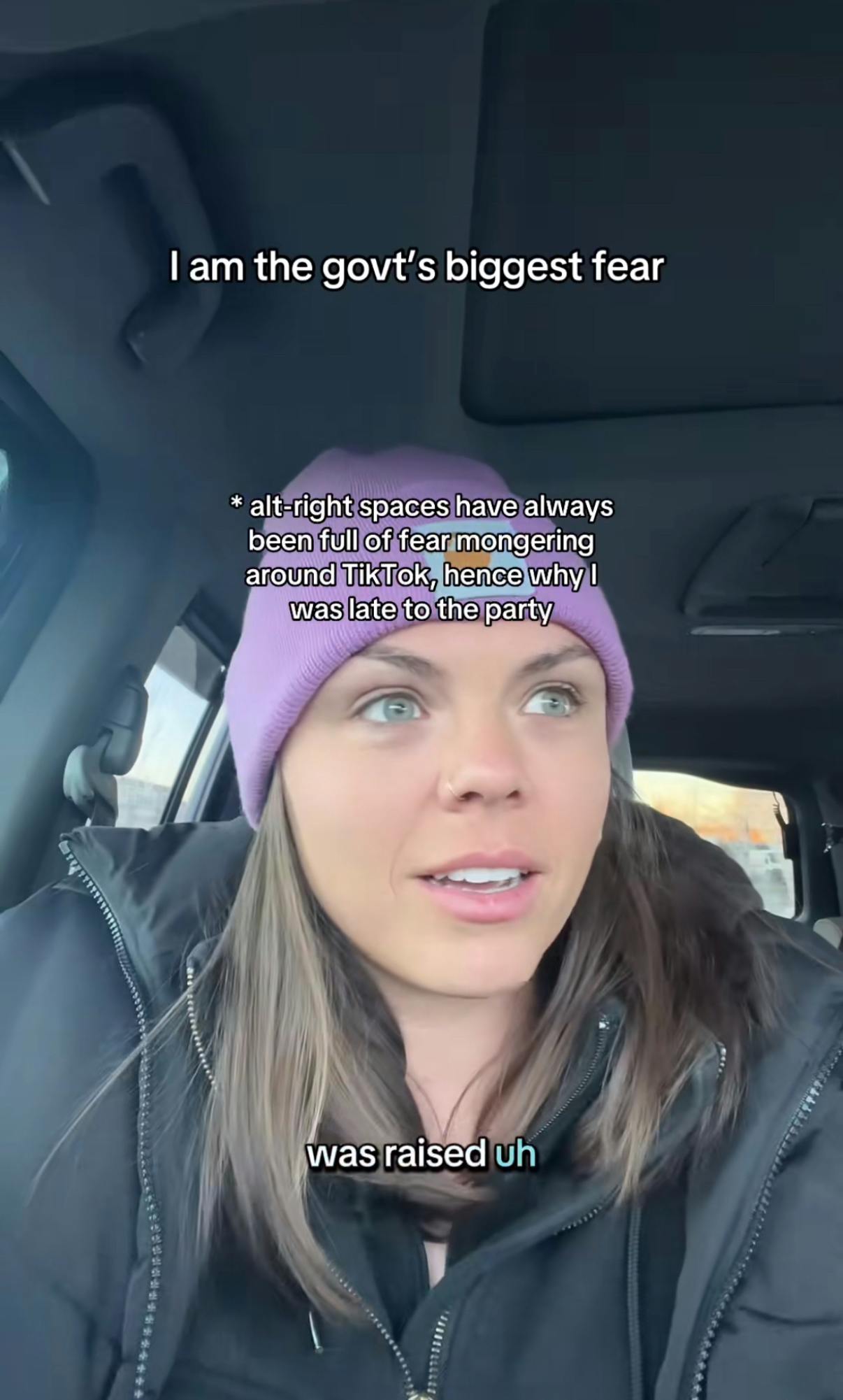 A woman in a pink beanie sitting in her car. Text overlay reads, 'I am the govt's biggest fear.'