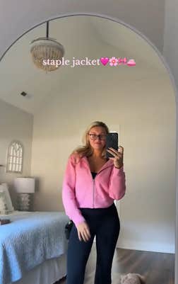 A blonde woman in a pink dupe Scuba hoodie posing for her camera.
